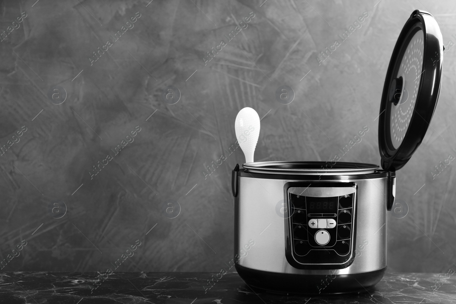 Photo of Modern powerful multi cooker on table against grey background. Space for text