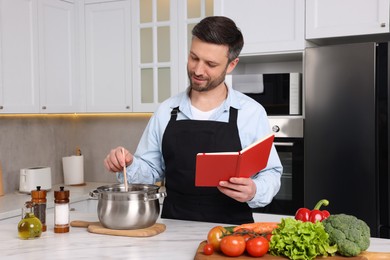 Man cooking by recipe book in kitchen