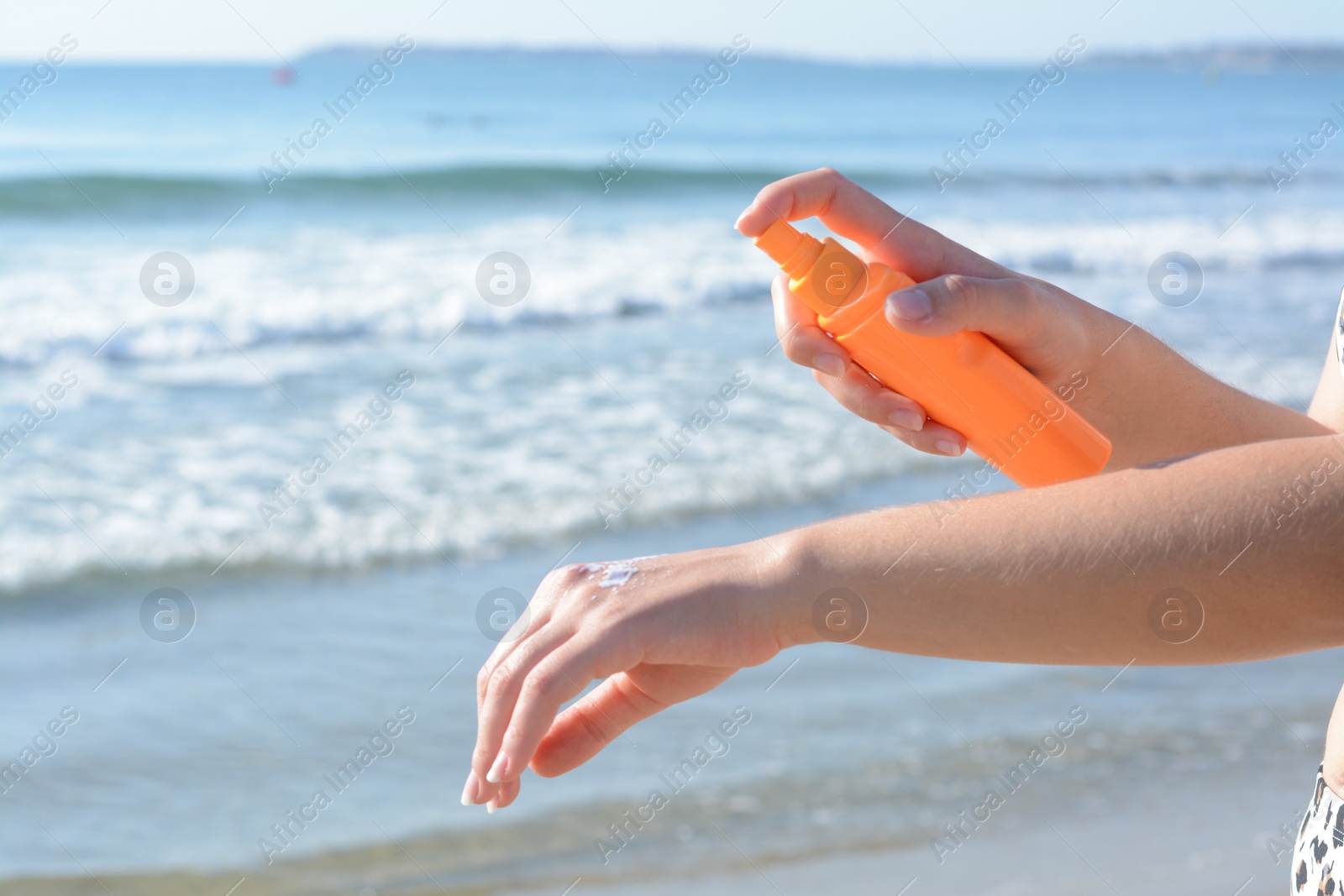 Photo of Woman applying sun protection cream on her hand at beach, closeup