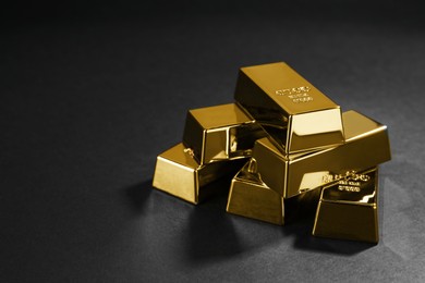 Photo of Many shiny gold bars on black background. Space for text