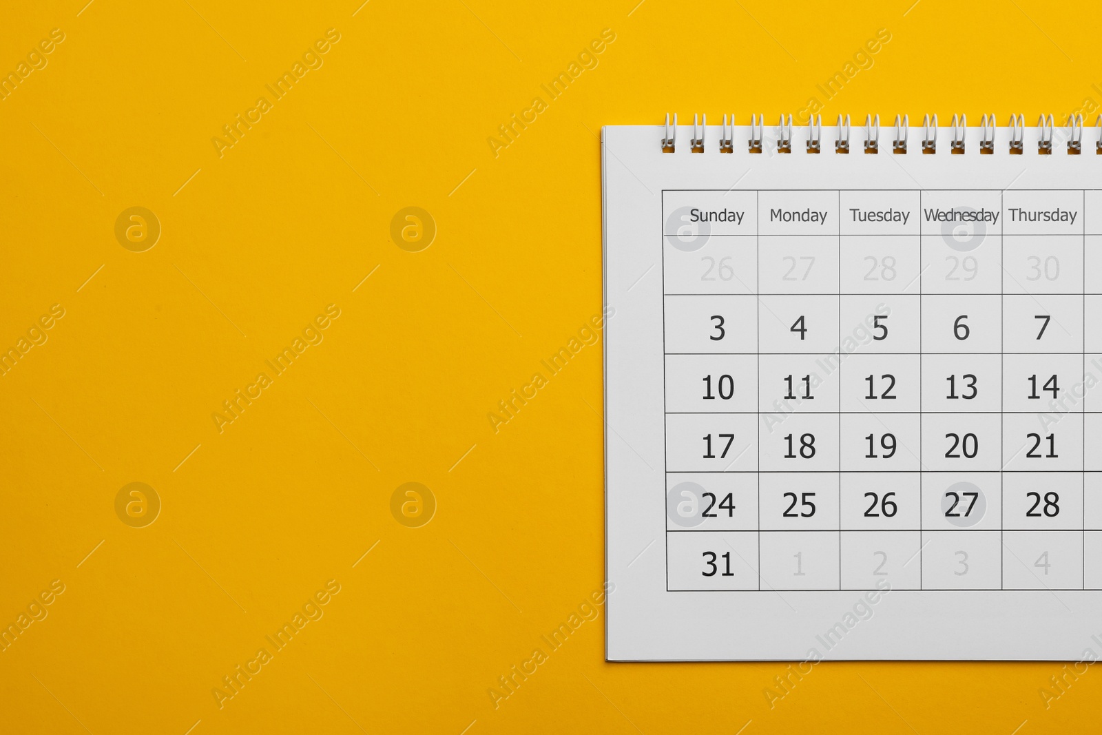 Photo of Paper calendar on yellow background, top view. Space for text