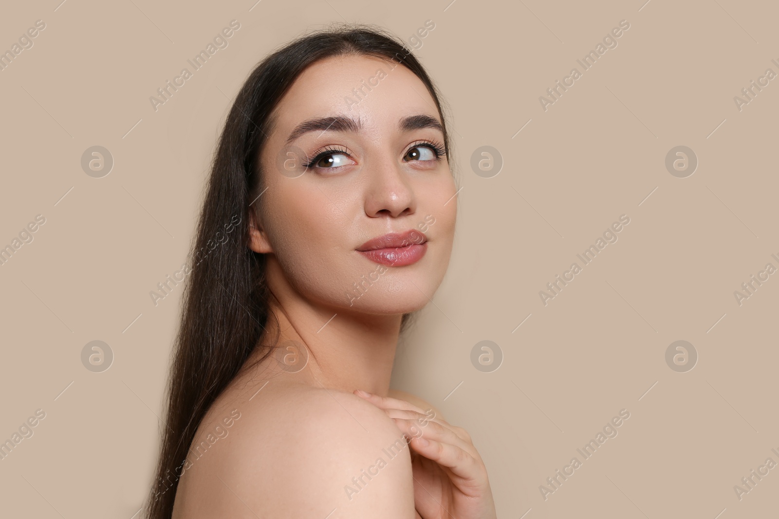 Photo of Portrait of beautiful young woman with elegant makeup on dark beige background. Space for text