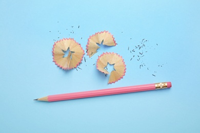 Photo of Pencil and shavings on blue background, flat lay