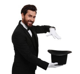 Happy magician showing magic trick with top hat on white background