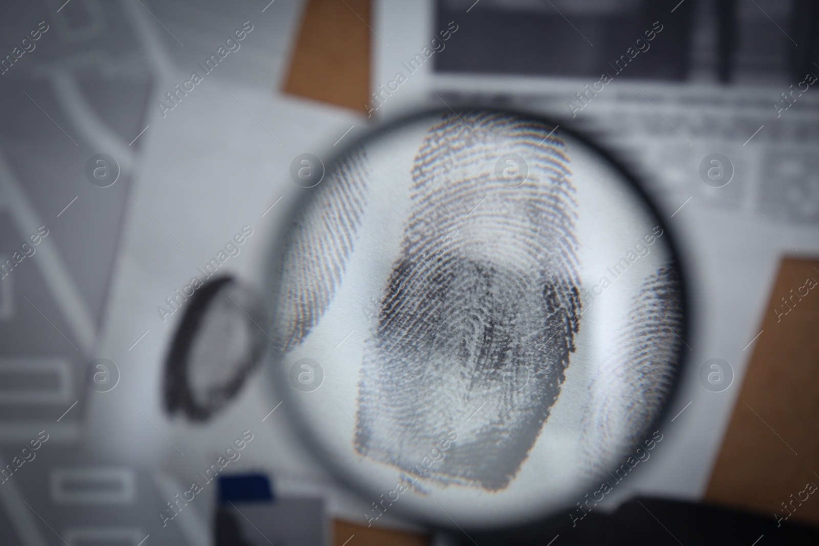 Photo of Looking through magnifying glass at fingerprints on detective board, closeup