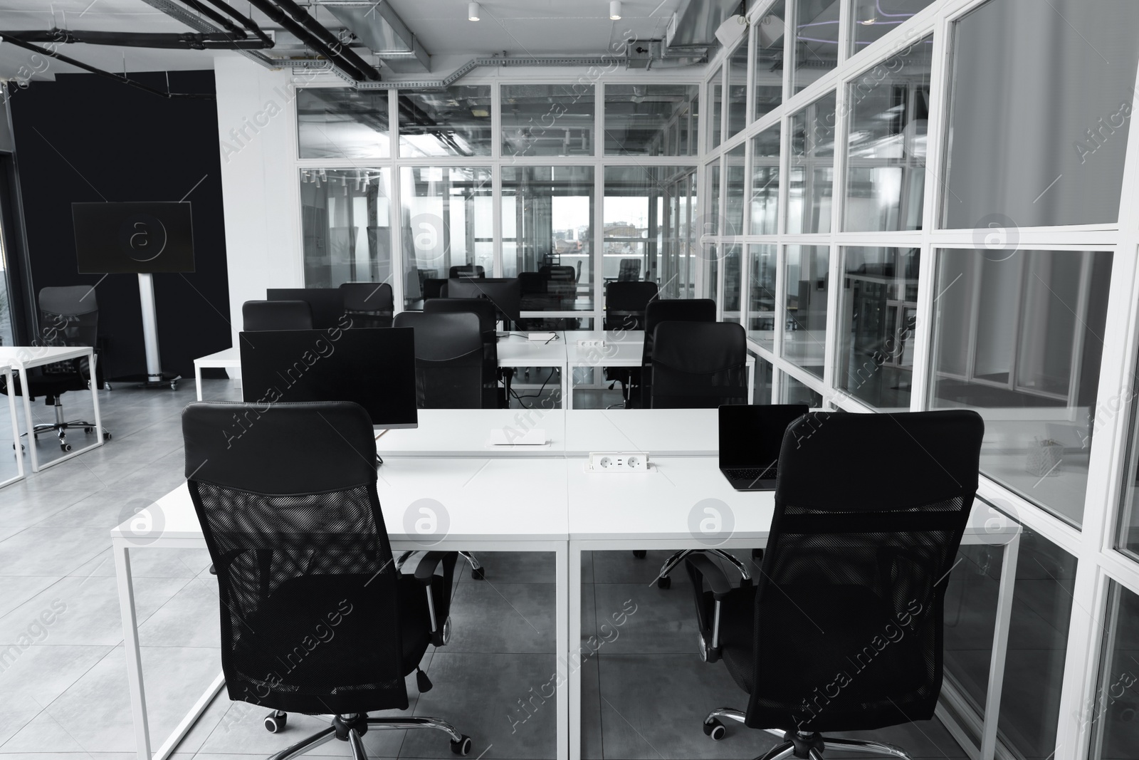 Photo of Stylish interior of open plan office. Workspace with computers, tables and chairs