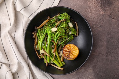 Tasty cooked broccolini with lemon and mushrooms on grey table, top view