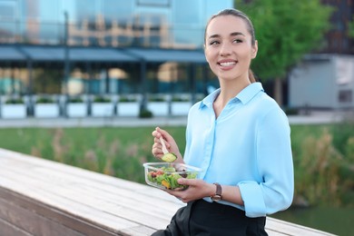 Smiling businesswoman eating lunch outdoors. Space for text