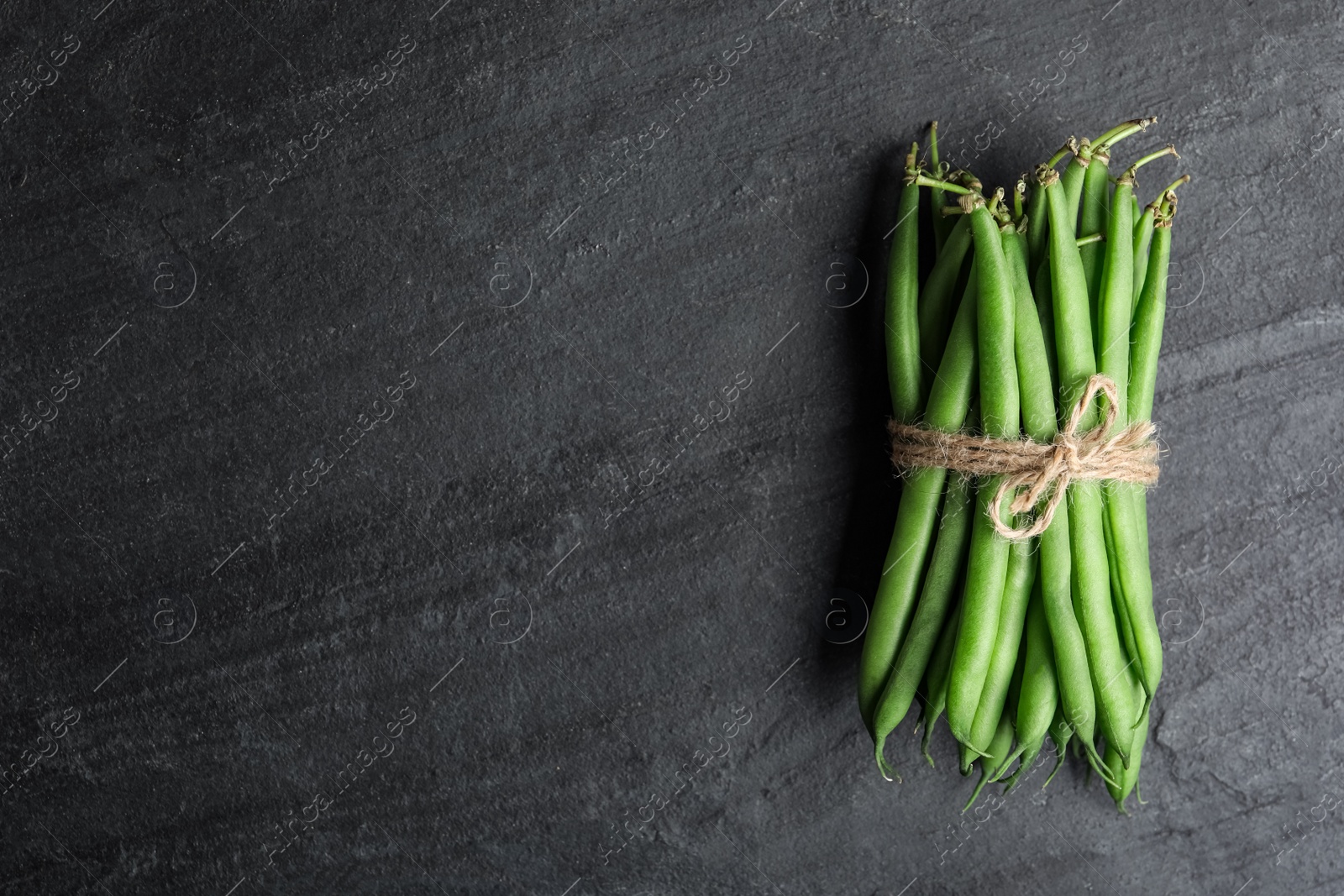 Photo of Fresh green beans on black table, top view. Space for text