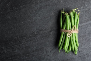 Photo of Fresh green beans on black table, top view. Space for text