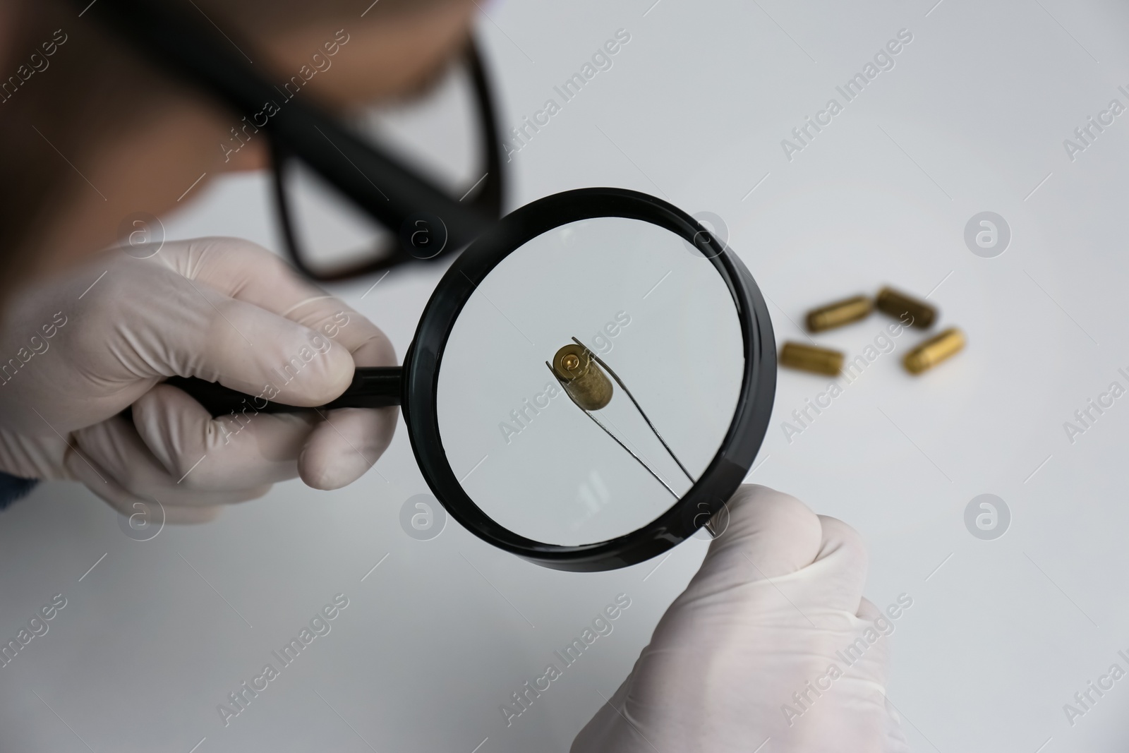 Photo of Detective exploring bullet shell with magnifying glass, closeup