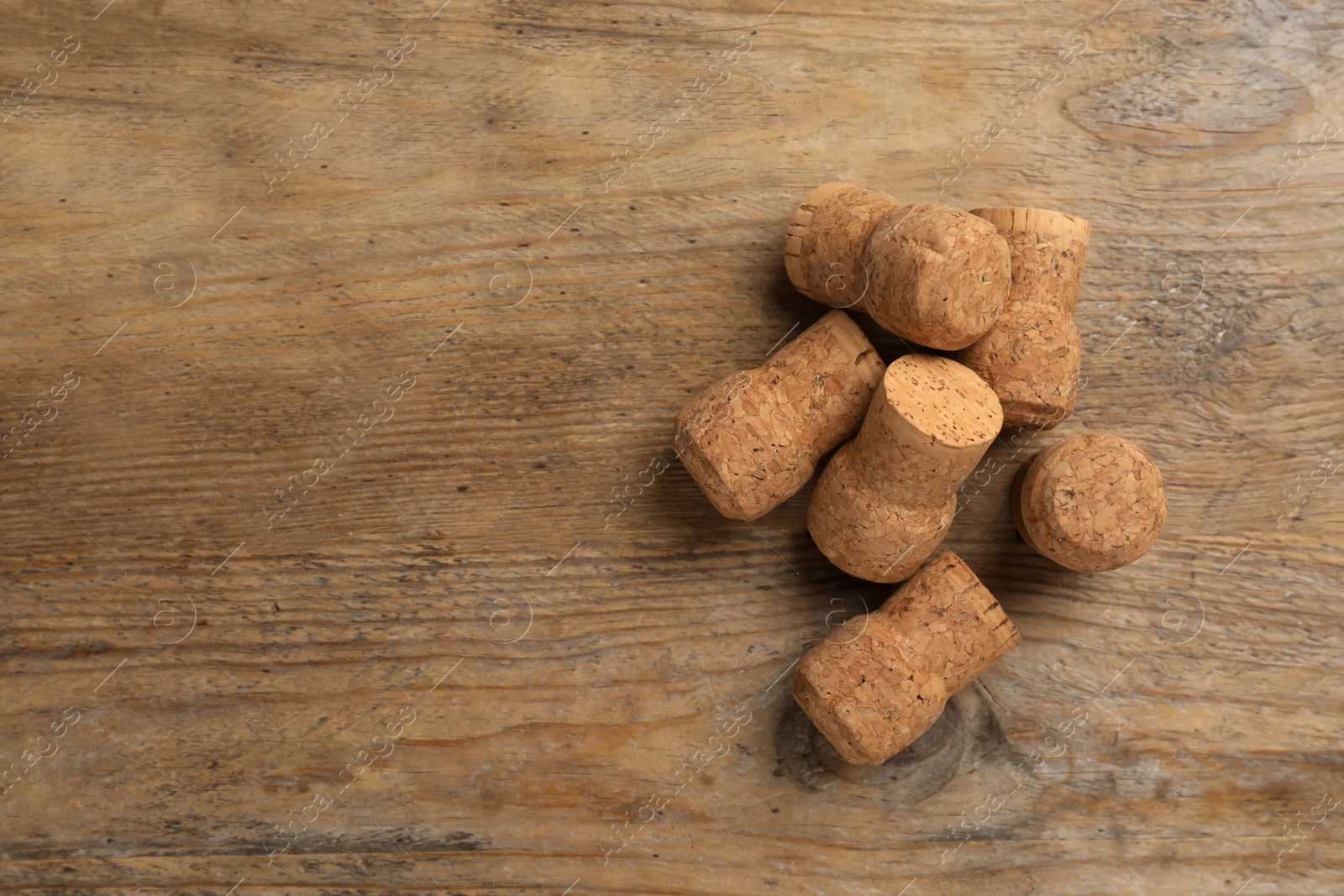 Photo of Sparkling wine corks on wooden table, flat lay. Space for text