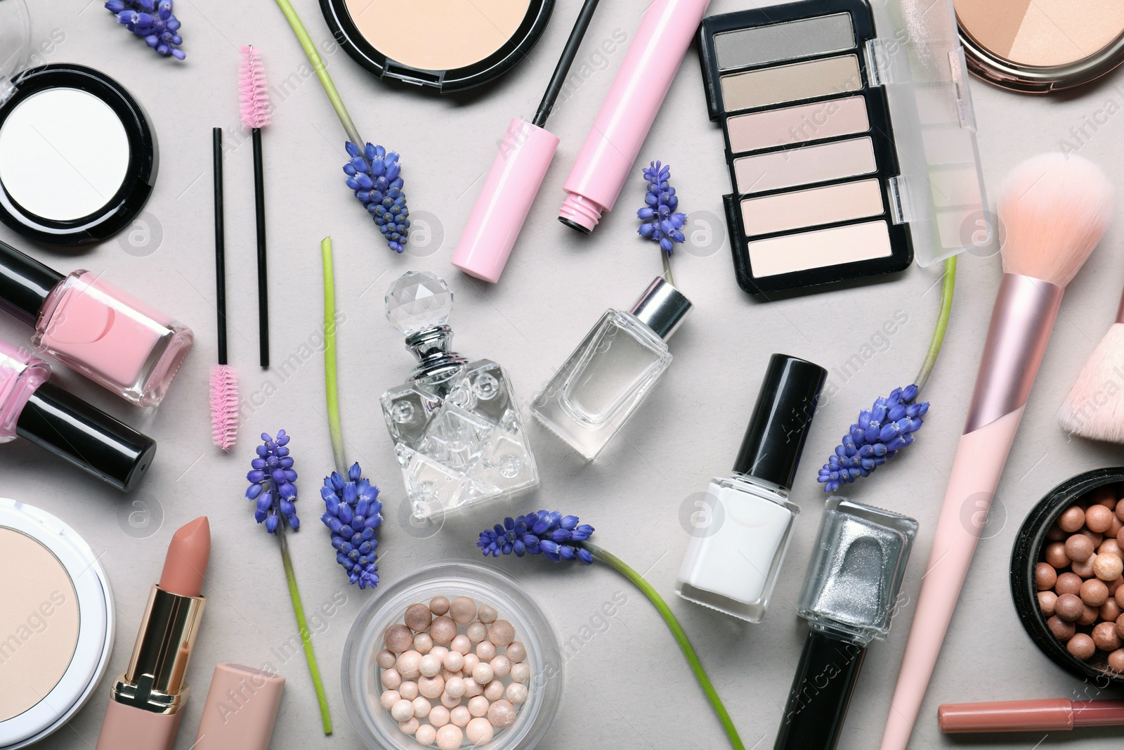 Photo of Flat lay composition with different makeup products and beautiful spring flowers on gray background