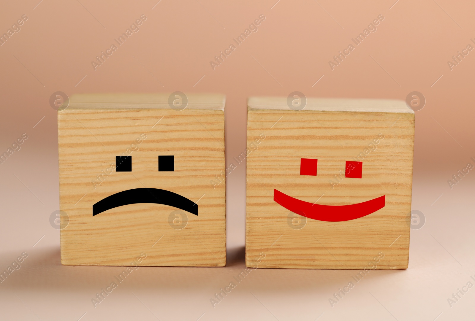 Image of Wooden cubes with sad and happy faces on beige background