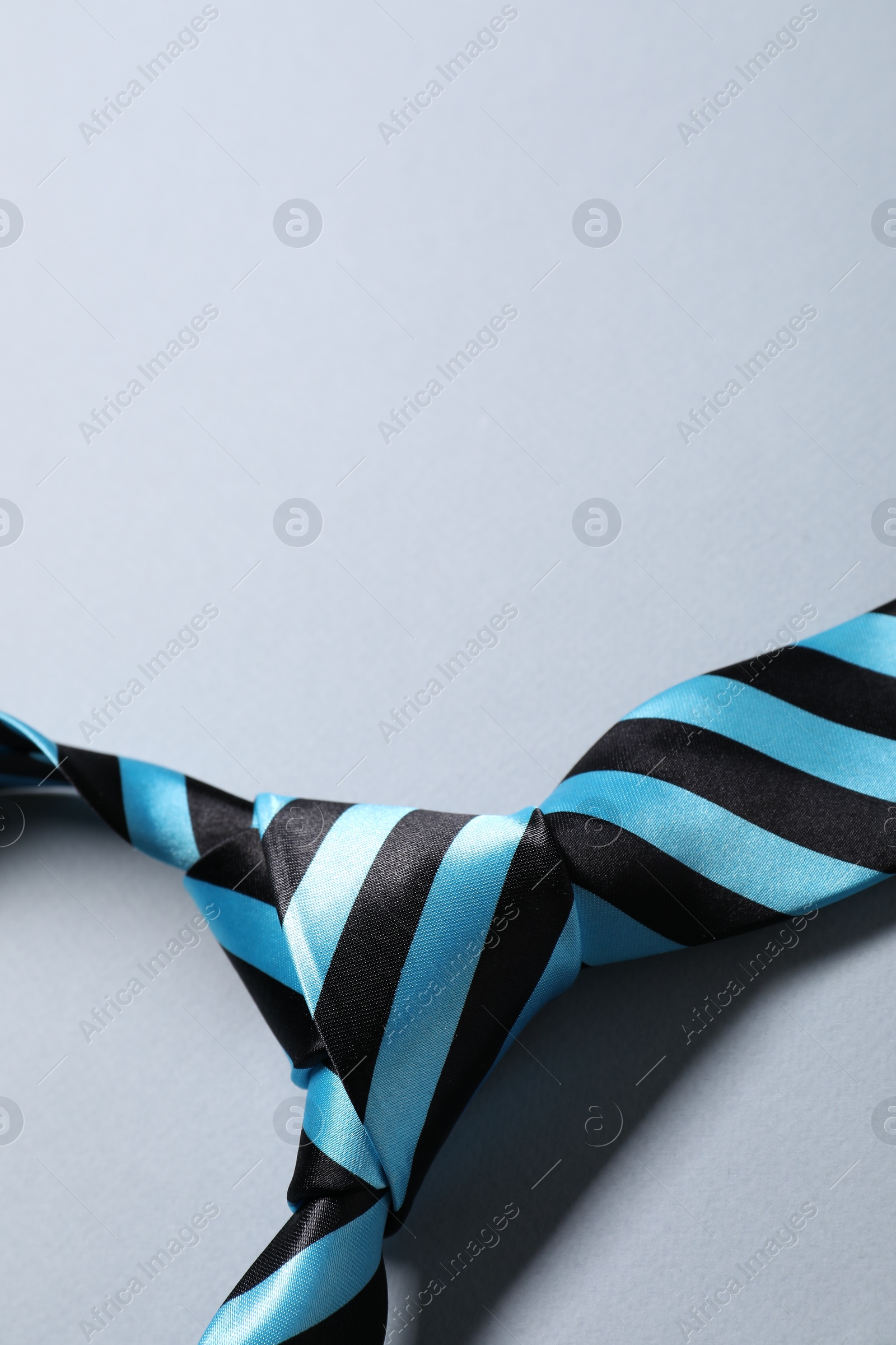 Photo of Stylish striped necktie on light grey background, closeup