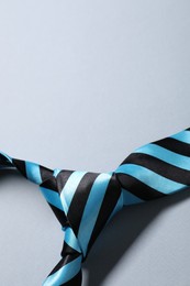 Stylish striped necktie on light grey background, closeup