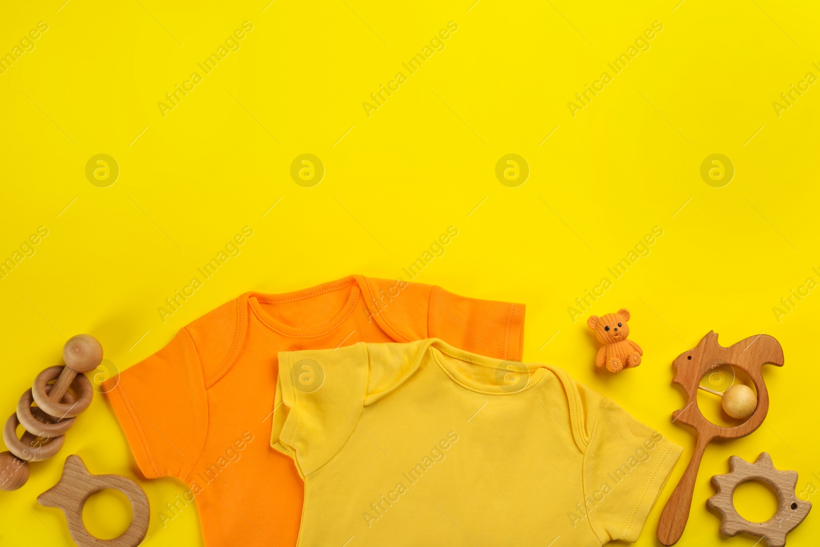 Photo of Flat lay composition with baby clothes and accessories on yellow background, space for text