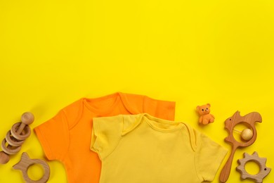 Flat lay composition with baby clothes and accessories on yellow background, space for text