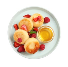 Delicious cottage cheese pancakes with fresh berries and honey on white background, top view