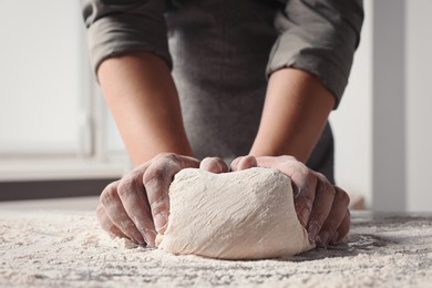 Man kneading dough at table in kitchen, closeup