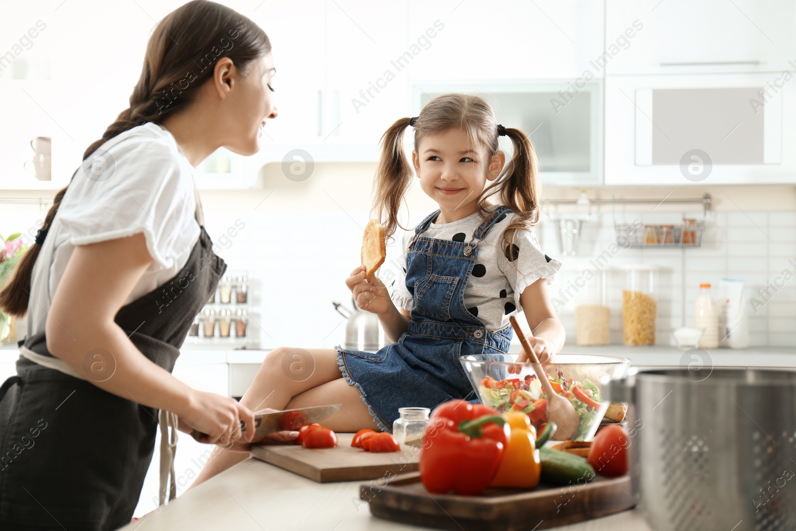 Photo of Young nanny with cute little girl cooking together in kitchen