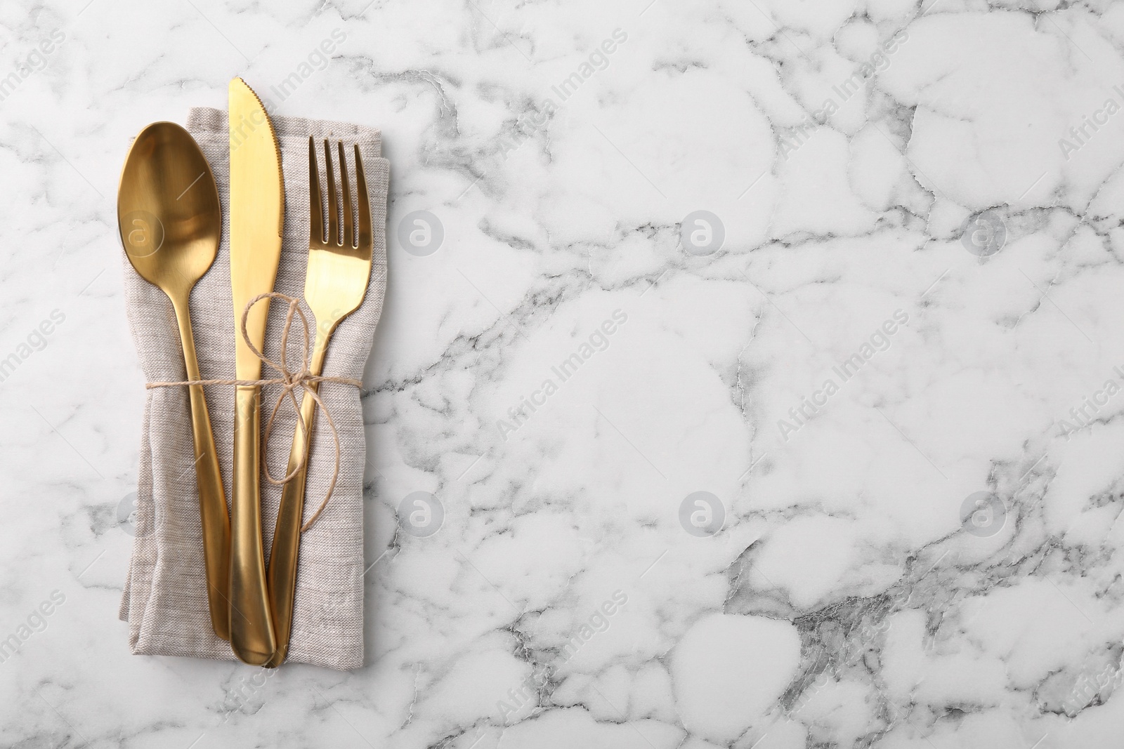 Photo of Set of stylish cutlery and napkin on white marble table, top view. Space for text