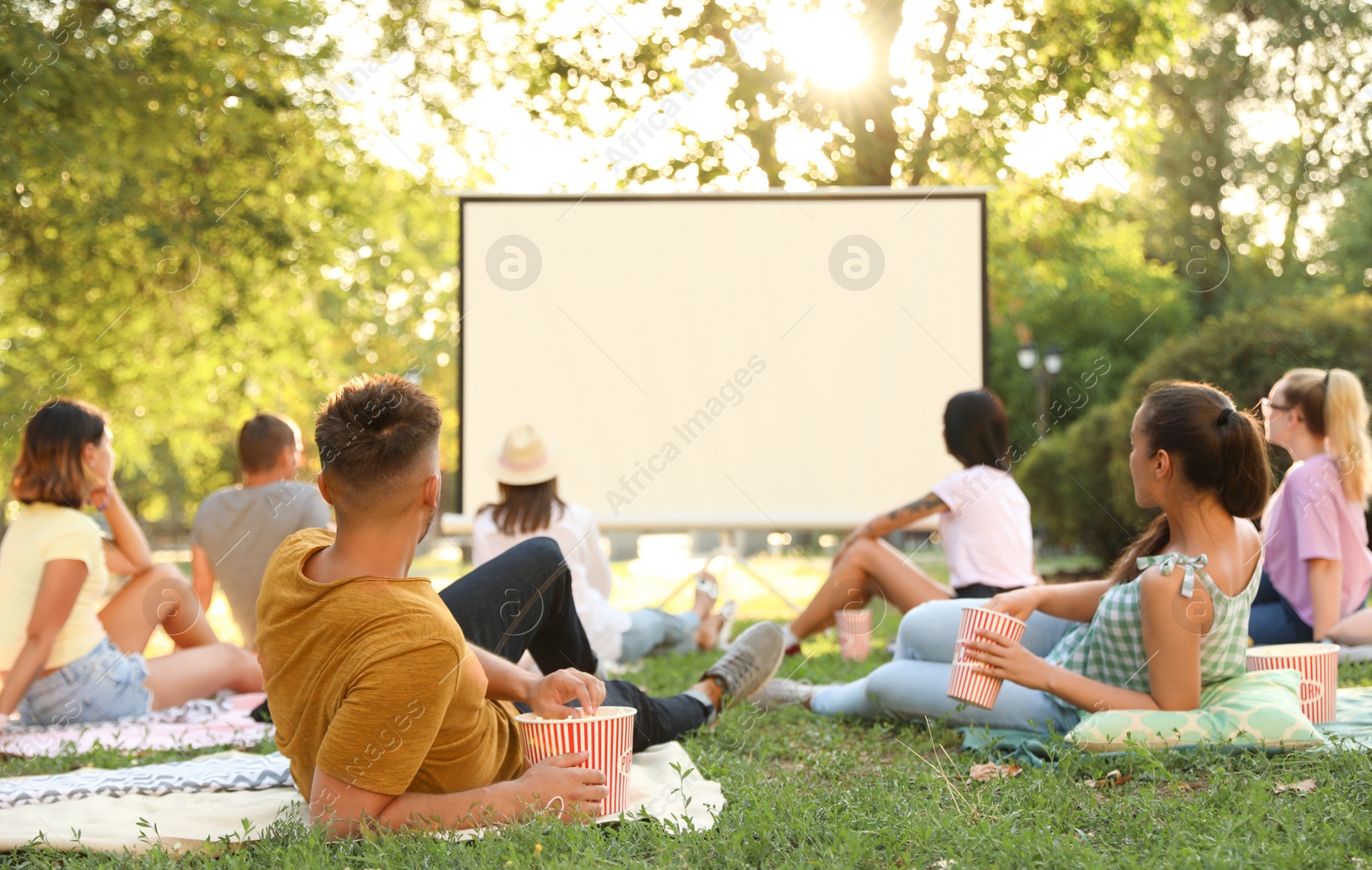 Photo of Young people watching movie in open air cinema. Space for text