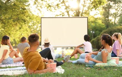 Photo of Young people watching movie in open air cinema. Space for text