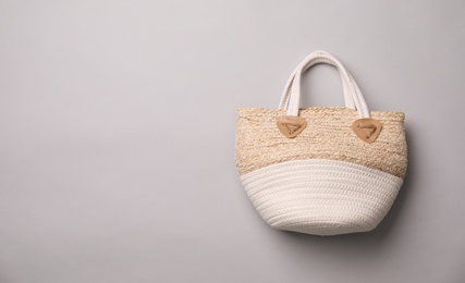 Photo of Stylish straw bag on grey background, top view with space for text. Summer accessory