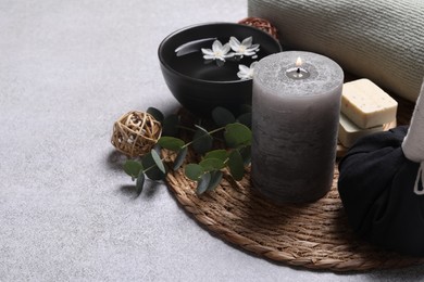 Beautiful composition with burning candle and spa products on light grey table. Space for text