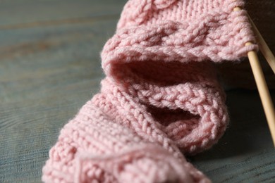 Photo of Pink knitting and needles on wooden table, closeup