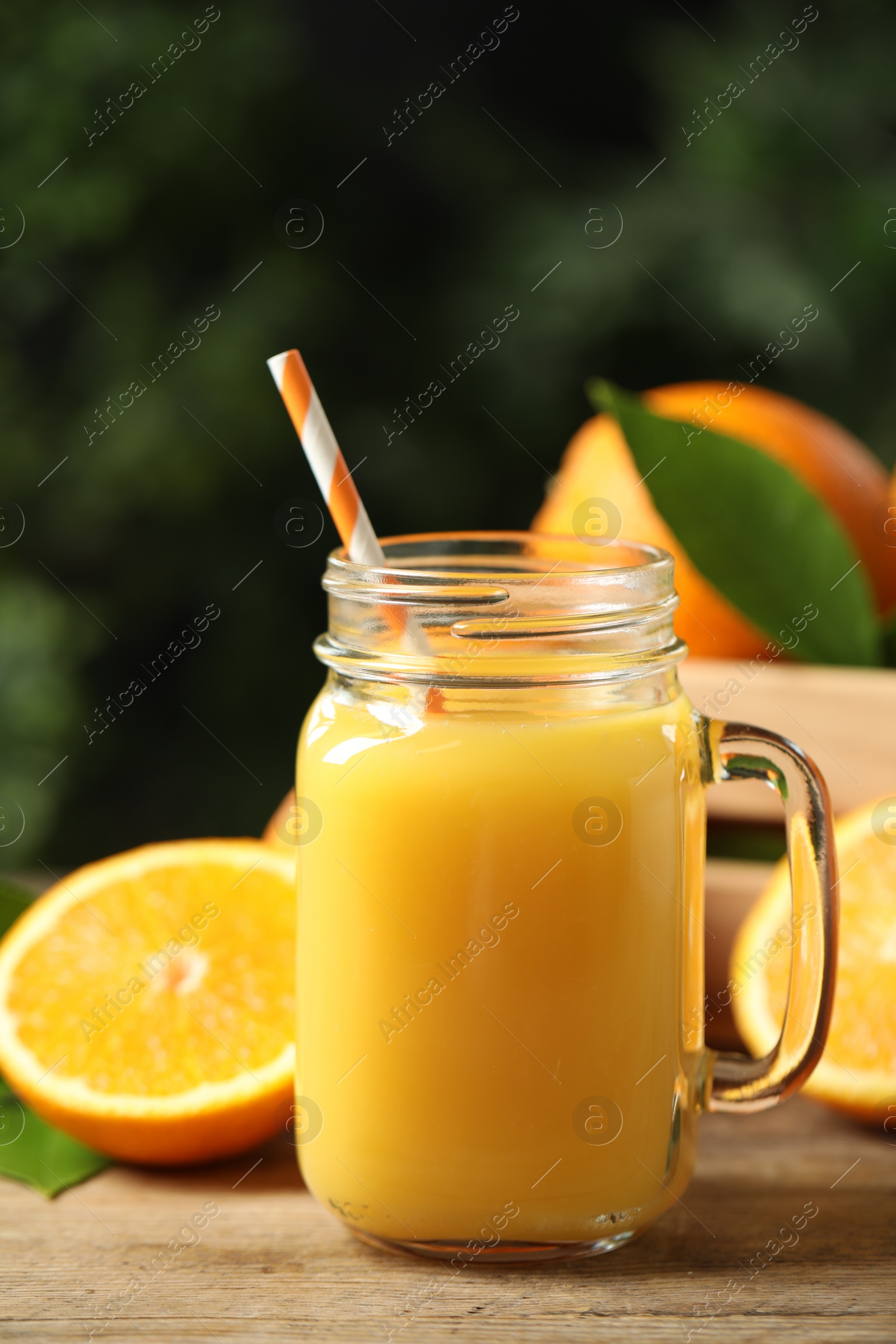 Photo of Mason jar of orange juice and fresh fruits on wooden table