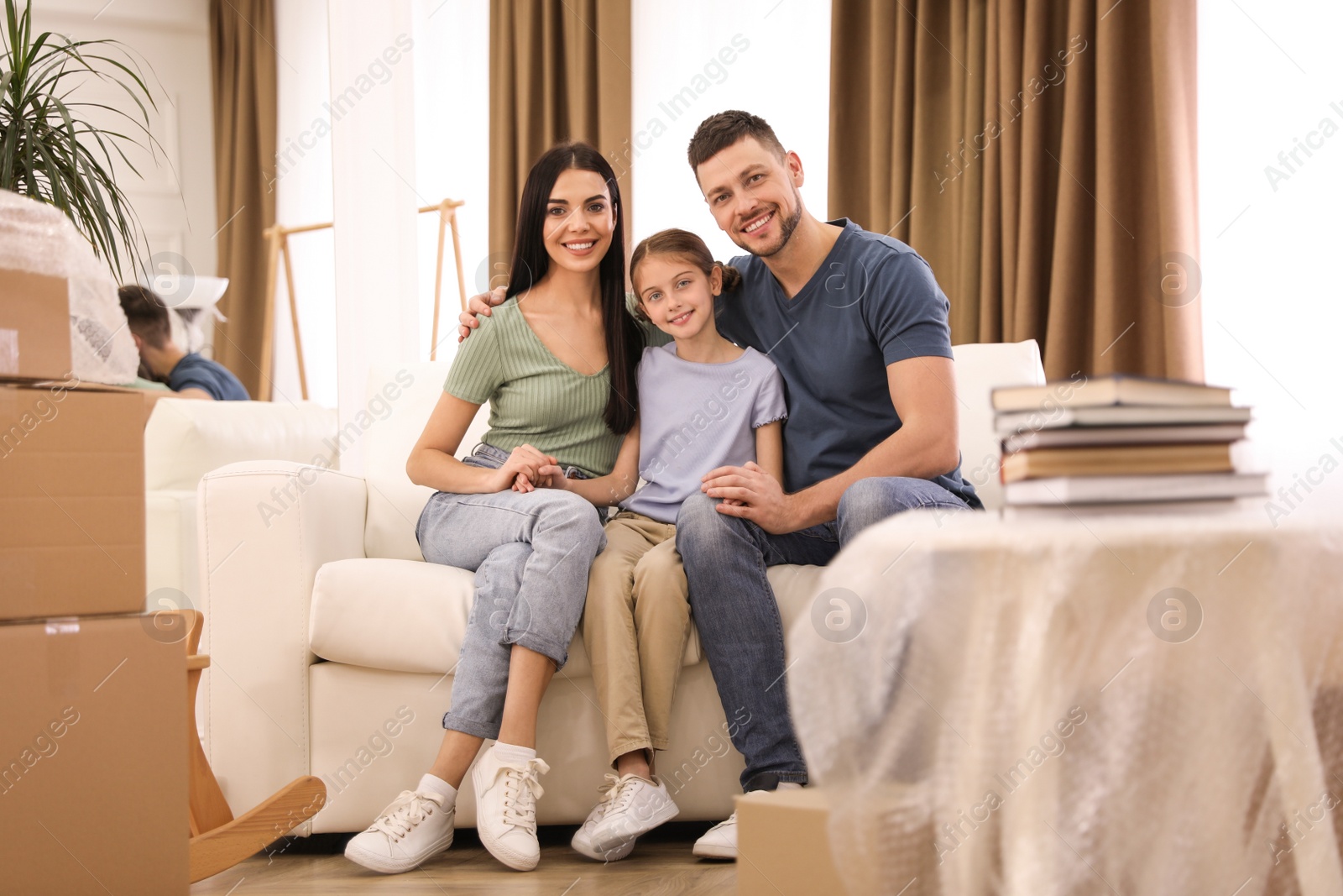 Photo of Happy family sitting on sofa in new house. Moving day