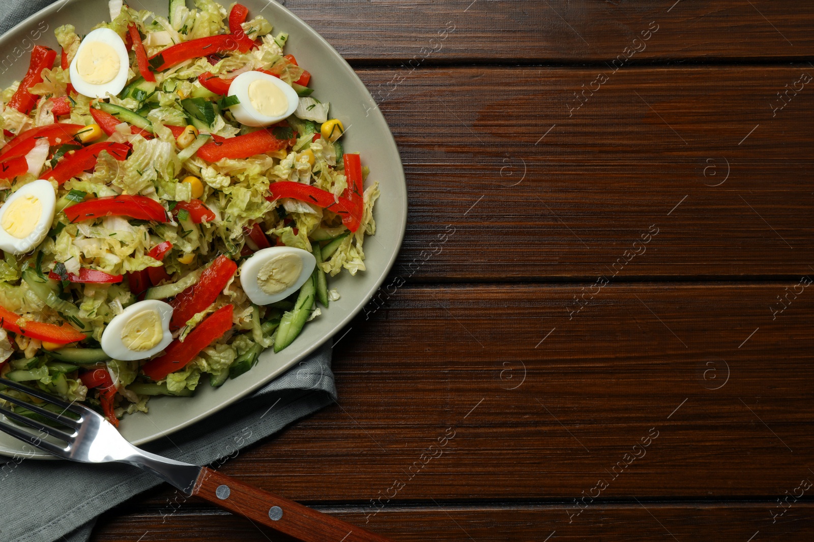 Photo of Delicious salad with Chinese cabbage and quail eggs served on wooden table, top view. Space for text