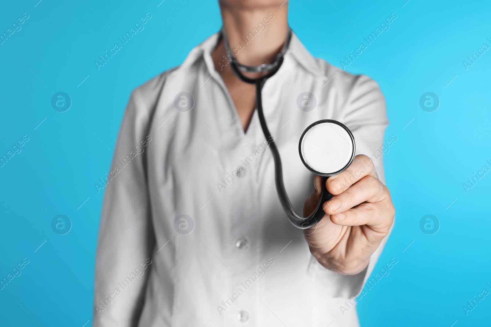 Photo of Female doctor holding stethoscope on color background, closeup. Medical object