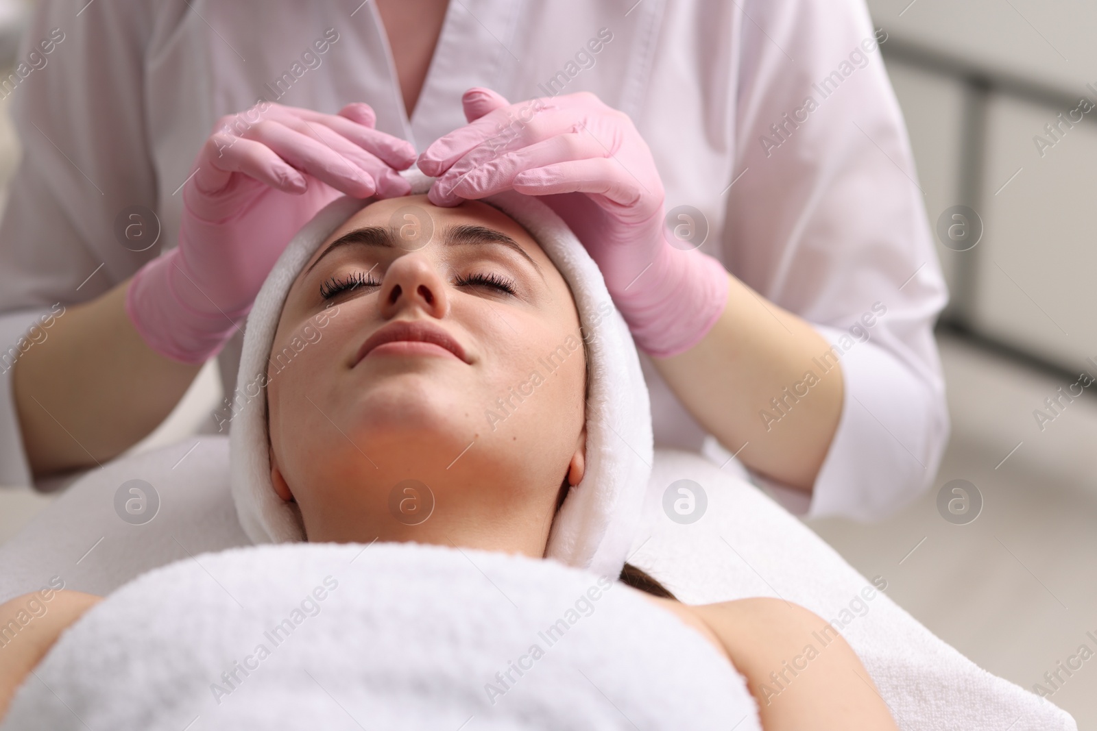 Photo of Cosmetologist making face massage to client in clinic, closeup