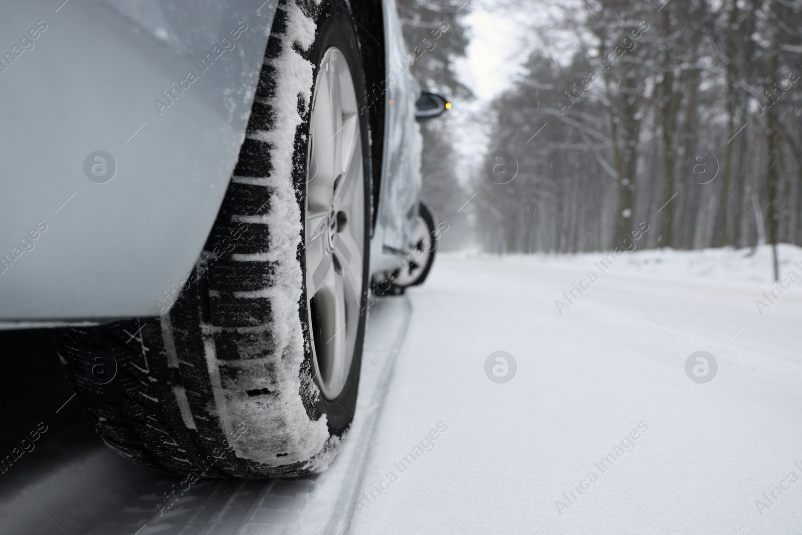 Photo of Car with winter tires on snowy road in forest, closeup. Space for text