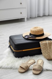 Photo of Suitcase packed for trip and summer accessories on floor indoors