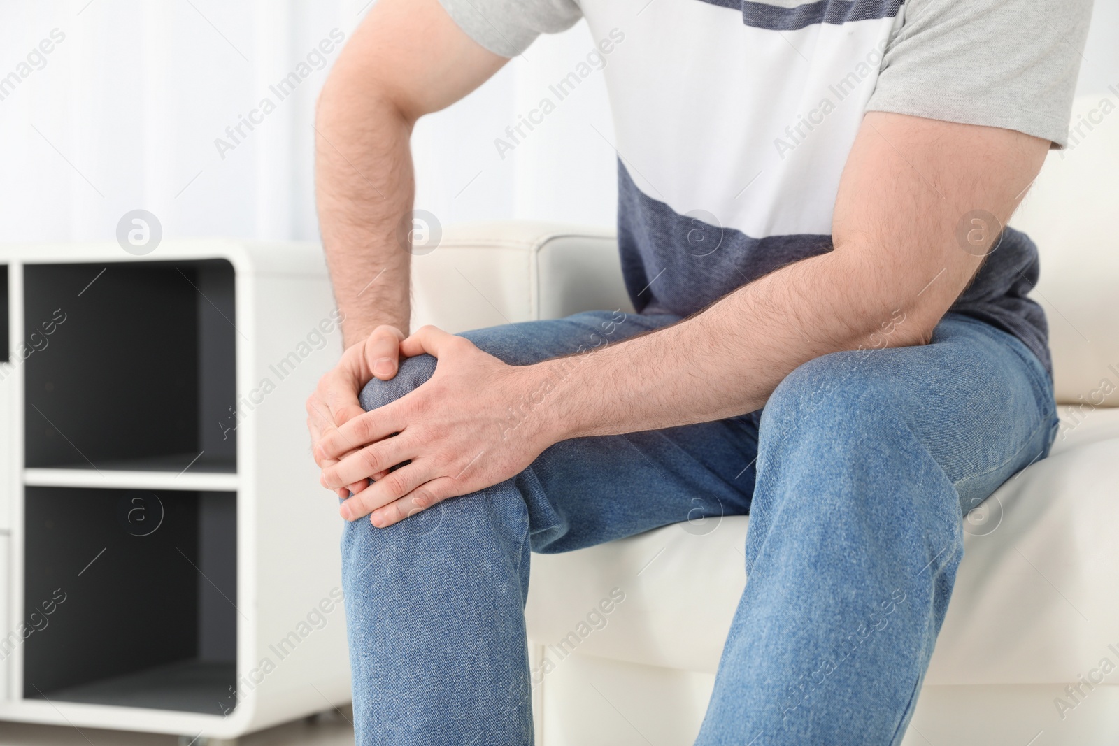 Photo of Young man suffering from leg pain indoors, closeup. Space for text