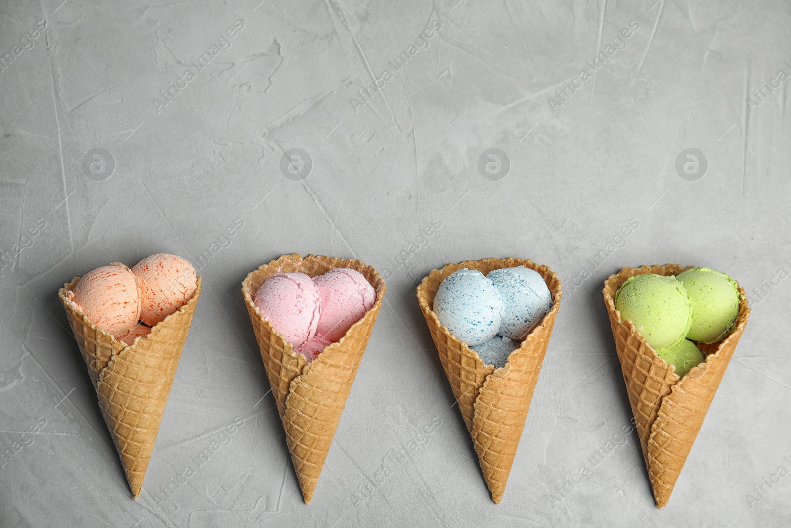 Photo of Flat lay composition with delicious ice creams in waffle cones on table, space for text