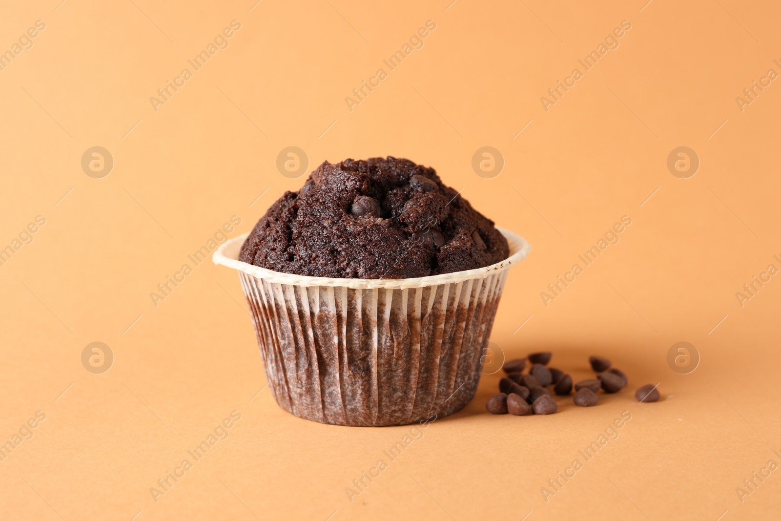 Photo of Tasty chocolate muffin on pale orange background