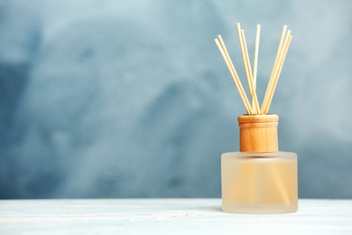Photo of Aromatic reed freshener on table against color background
