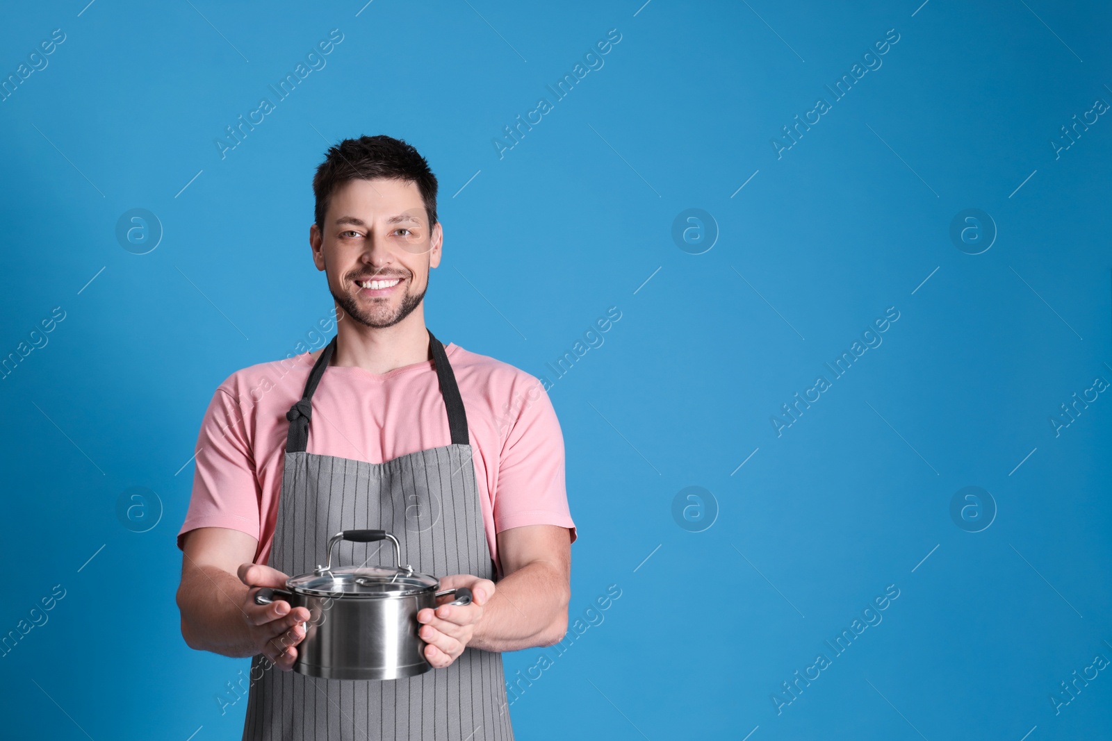 Photo of Happy man with pot on light blue background. Space for text