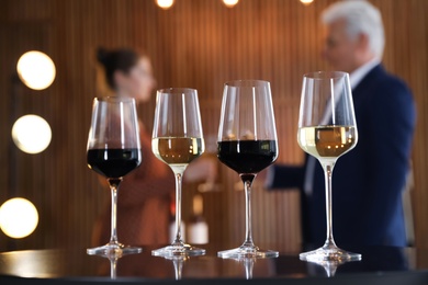 Photo of Glasses of different wines on table against blurred background