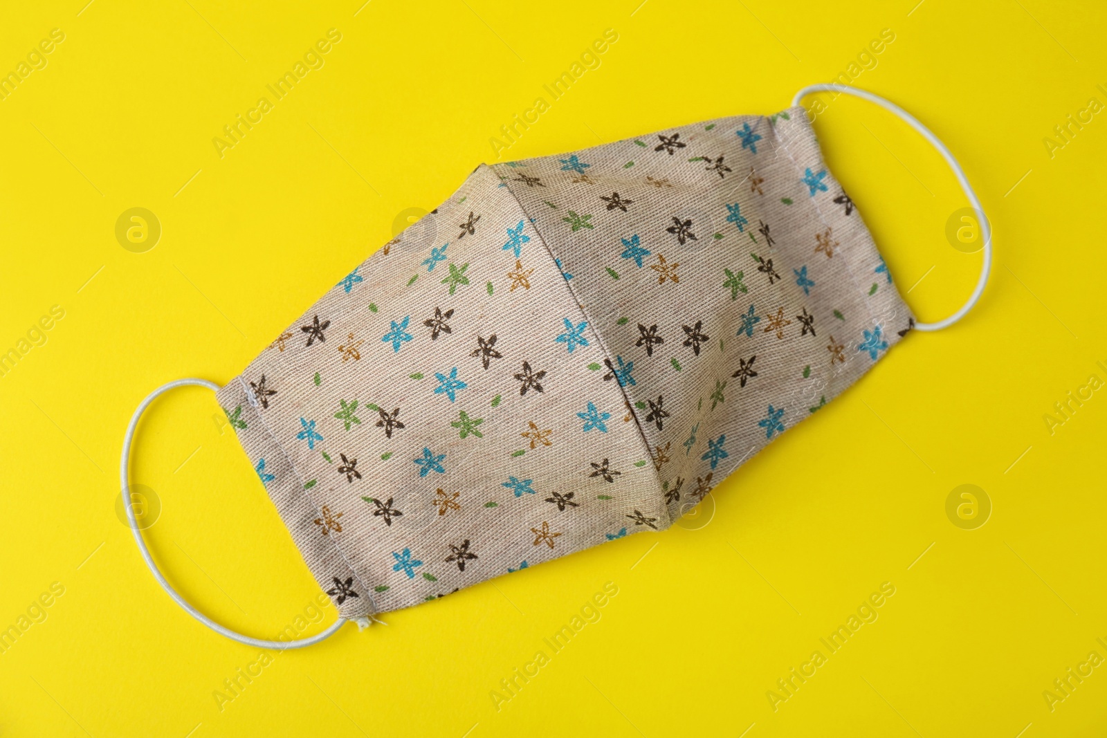 Photo of Homemade protective face mask on yellow background, top view