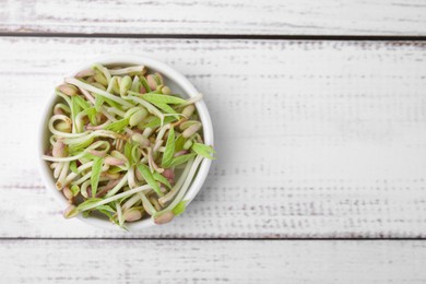 Mung bean sprouts in bowl on white wooden table, top view. Space for text