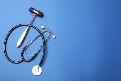 Photo of Reflex hammer, stethoscope and space for text on blue background, flat lay. Nervous system diagnostic