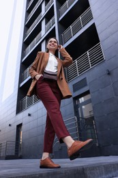 Photo of Young woman in formal clothes near building outdoors, low angle view