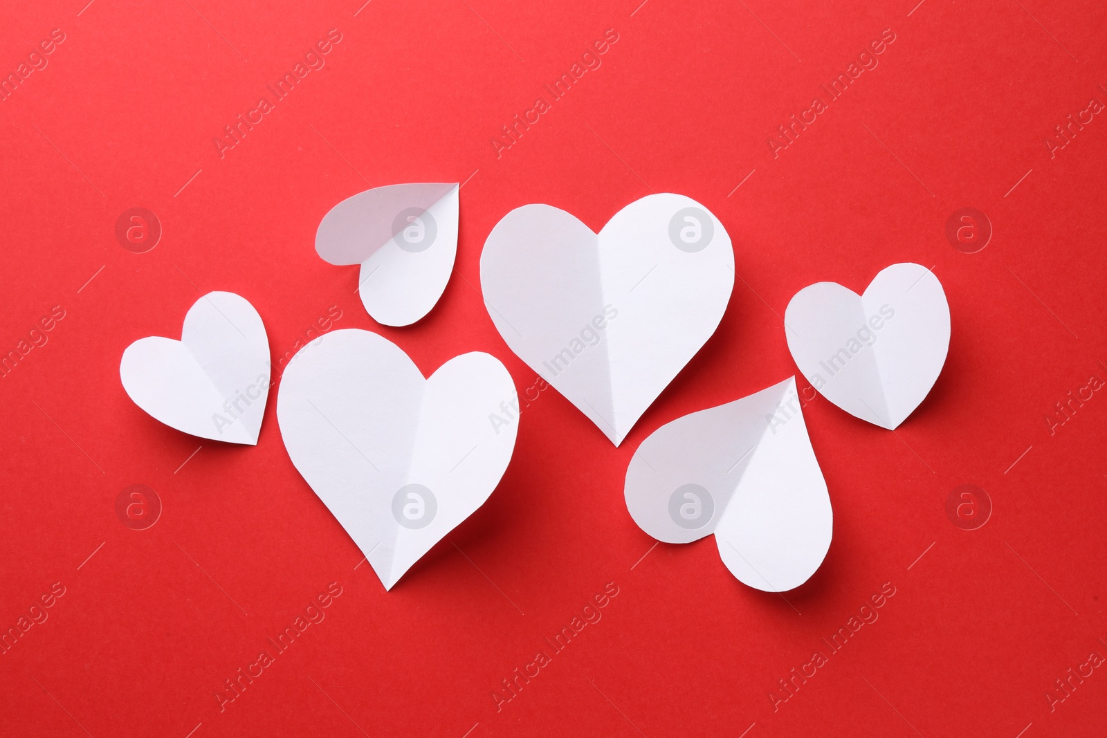 Photo of White paper hearts on red background, flat lay