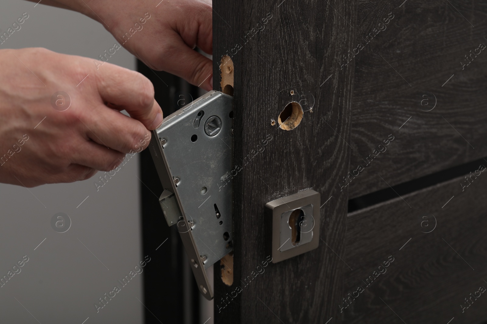 Photo of Handyman changing door handleset indoors, closeup view